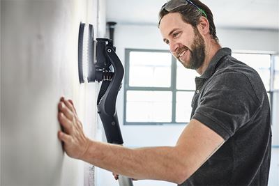 A painter sands a wall with the Planex long-reach sander